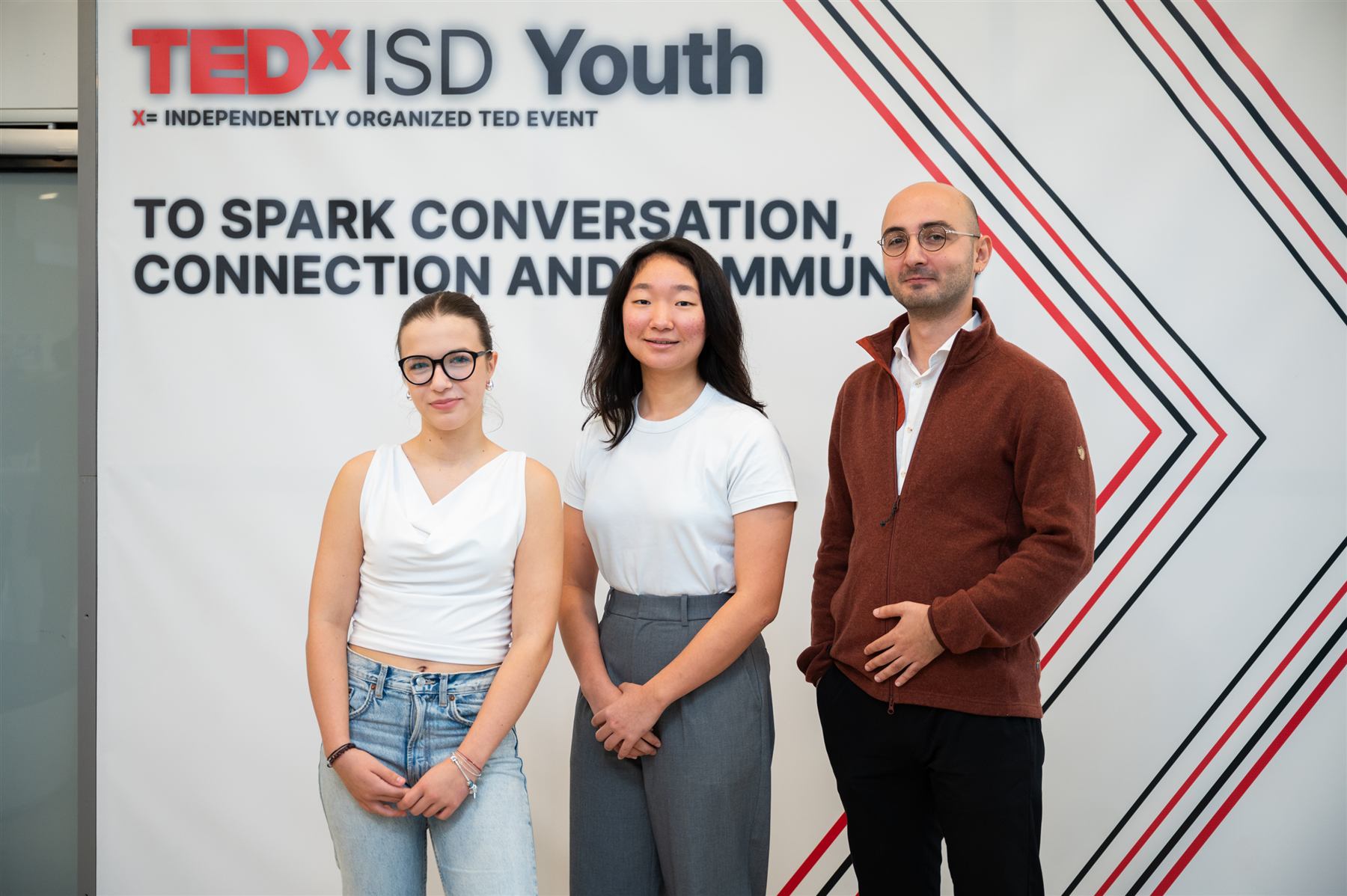 Three student organizers posing in front of the TEDxISD Youth banner